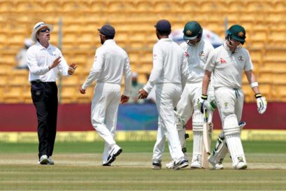 Virat Kohli speaks to the umpire as Steven Smith (right) walks off the ground after being dismissed in Bengaluru
