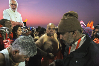 A Modi cutout looms over devotees as they take a holy dip